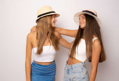 Friends forever. Two cute lovely girl friends in straw hat posing with smile on white backgroundの写真素材