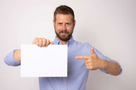 Portrait of happy smiling young business man showing blank signboard over white background.