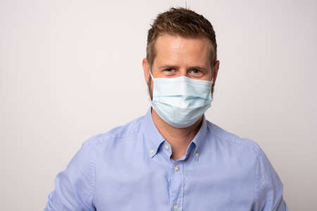 Portrait of handsome young businessman with surgical medical mask looking at camera.の写真素材