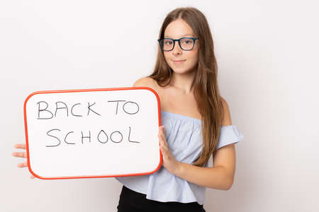 Young girl wearing glasses holding white board over white background. Back to school concept.の写真素材