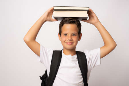 Smiling schoolboy holding books on white background. Back to school concept.の写真素材