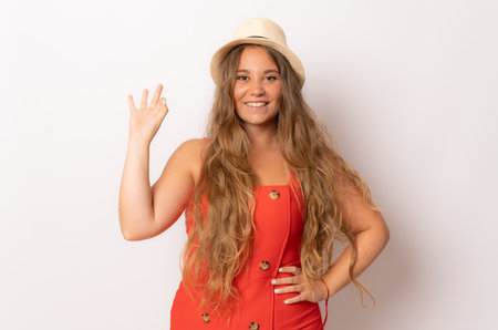 Smiling young woman in straw hat with okay sign gesture isolated over white background.の写真素材