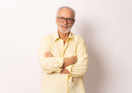 Senior man wearing yellow shirt with arms folded isolated over white background.の写真素材