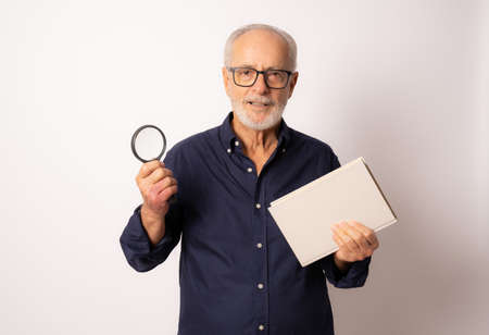 Portrait elderly man reading a book with magnifying glass over white background.の写真素材