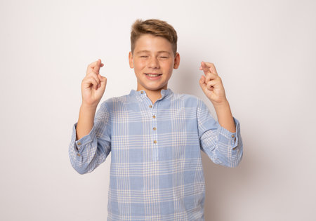 Young boy crossing fingers for having luck isolated over white background.の写真素材