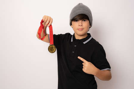 Cute child boy showing his gold medal isolated over white background.の写真素材