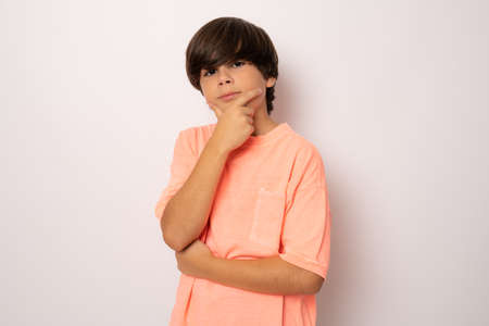 Pensive child boy in casual t-shirt isolated over white backgroundの写真素材