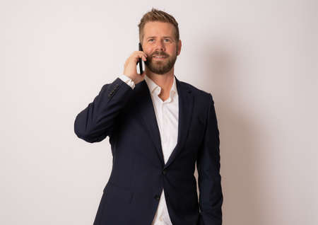 Young smiling business man talking on the phone over isolated background.の写真素材