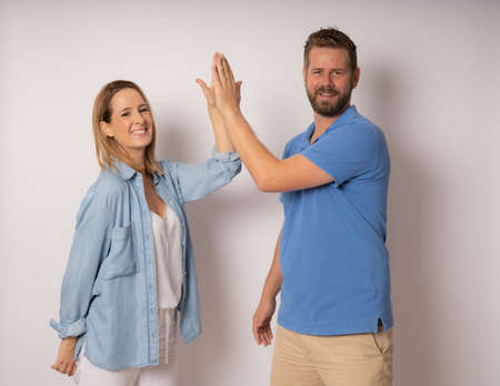 Profile side view of happy man making greeting gesture give high five with smiling and young woman.の写真素材