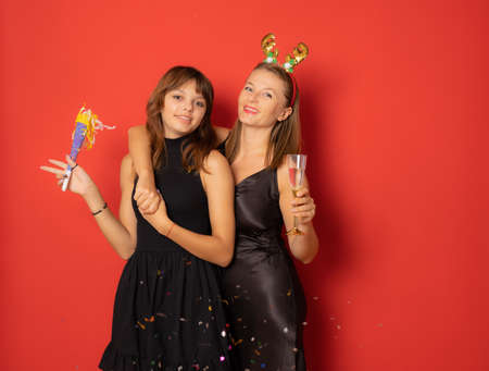 Mother and daughter celebrating new years eve together over red background.の写真素材