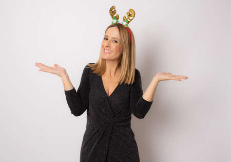 Portrait of an excited cheerful woman in christmas hat and dress standing isolated over white backgroundの写真素材