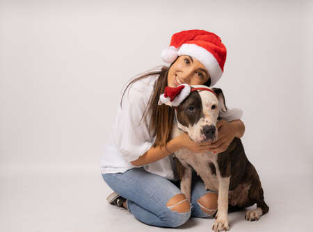 Portrait of happy girl with her dog in santa hat isolated on white backgroundの写真素材