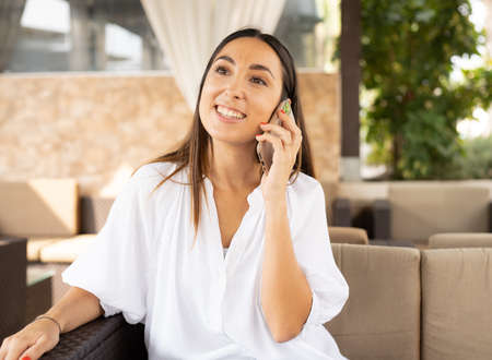 Happy casual woman calling on the phone in a restaurant terrace outdoorsの写真素材