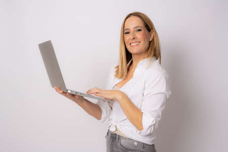 Image of cheerful young woman standing isolated over white background using laptop computer. Looking camera.の写真素材