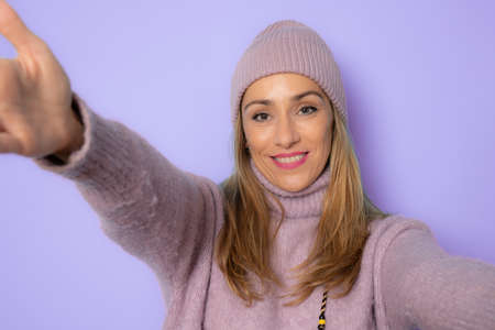 Young caucasian woman in winter clothing isolated over purple background feels confident giving a hug to the camera.の写真素材