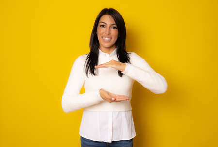 Middle age woman over isolated background holding something with both hands, product presentation.の写真素材