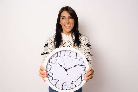 portrait of a beautiful young woman holding a big clock isolated over white background.の写真素材
