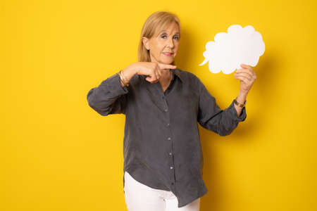 Senior woman holding blank sign isolated over yellow background.の写真素材