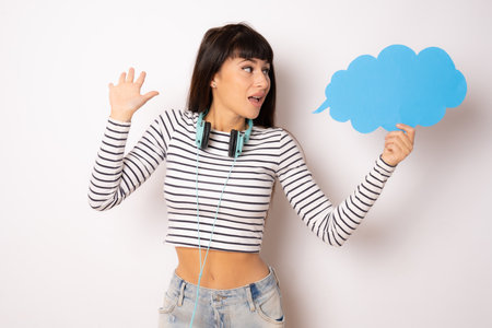 Young amazed woman in striped t-shirt showing paper cloud isolated over white background.の写真素材