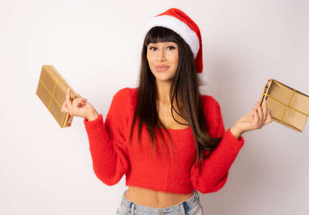Beautiful young woman in santa hat holding gift boxes isolated over white background.の写真素材