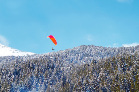 Landscape of mountains against the blue sky and white clouds. Forest of pine trees. Paratrooper...