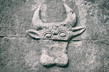 The background of an ancient memorial plate with the image of a bull. Old gray monument. Bright abstract background ideal for any designの写真素材