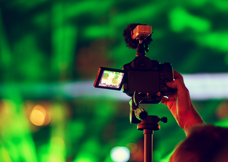 Blurred silhouette of camcorder and cameraman. Youth Music Festival of pop music. Laser show on the stage. The crowd of fans. Bright abstract background ideal for any design. Blurred bokeh backgroundの写真素材
