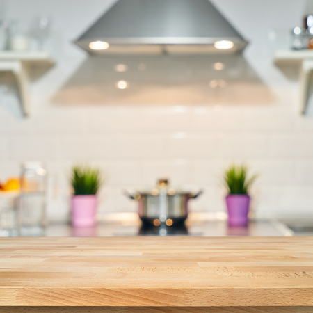 A wooden table top of the kitchen table on a blurry background of the kitchen interior. Bright interior decoration of home cooking. Bright ready-made picture for your individual designの写真素材