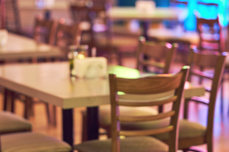 Blurred restaurant or cafe background. Tables and chairs in the lobby of the mall. Visitors to the...