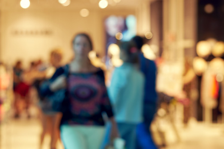 Blurred beautiful lobby at the malls. Big sales on Black Friday for Christmas. Blurred showcases fashion boutique with clothes. Shoppers in the store are reviewing the presented clothesの写真素材