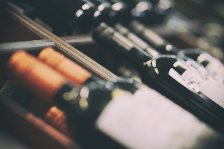 Blurred racks with bottles of red wine. Shelves with bottles of wine in a large grocery supermarket. Basic background for design