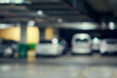Blurred spacious underground parking for car buyers in a large modern shopping mall. Bright abstract background ideal for any designの写真素材