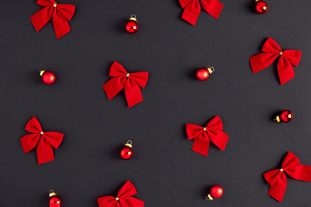 Holiday postcard. Christmas pattern of red bows and balls on a dark-gray backgroundの写真素材