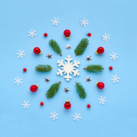 Christmas card. Xmas ornament from snowflakes, red balls, twigs of a Christmas tree, red beads and shining stars laid out in a circle on a blue backgroundの写真素材