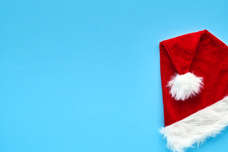 Christmas card. A bright red Santa Claus hat lies folded on a blue background. Background for your text and designの写真素材