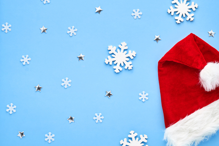 Christmas card. A bright red Santa Claus hat, folded, lies on a blue background with figures of white snowflakes, shiny stars. Background for your text and designの写真素材