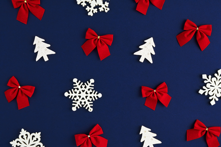 Holiday postcard. Christmas pattern of red bows and white snowflakes and xmas trees on a dark blue backgroundの写真素材