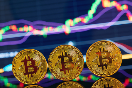Golden bitcoin are stacked on a bright background of business graphs close-up. Bitcoin cryptocurrency. Anonymousの写真素材