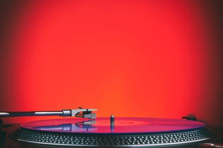 Turntable vinyl record player in the red light. Needle on the plate. Sound technology for DJ to mix & play music. Light purple vinyl recordの写真素材