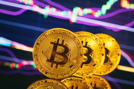 Golden bitcoin are stacked on a bright background of business graphs close-up. Bitcoin cryptocurrency. Anonymousの写真素材