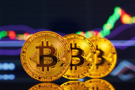 Golden bitcoin are stacked on a bright background of business graphs close-up. Bitcoin cryptocurrency. Anonymousの写真素材