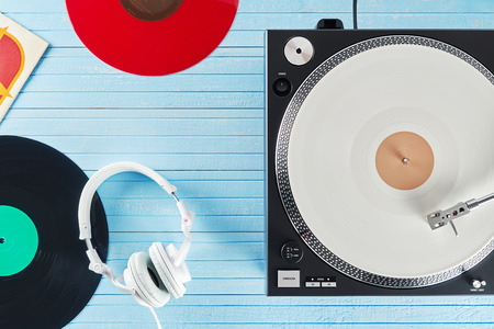 Turntable vinyl record player and white headphones on the background blue wooden boards. Sound...