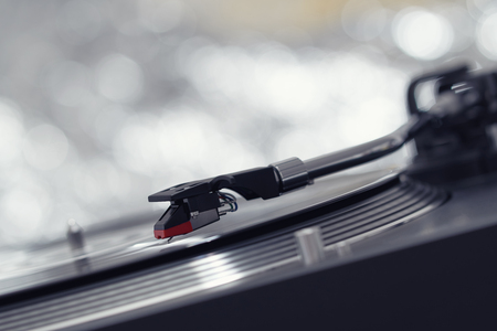 Turntable vinyl record player on the background of a sunset over the lights city. Sound technology for DJ to mix & play music. Black vinyl record. Vintage vinyl record player. Needle on a vinyl recordの写真素材
