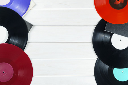 Holiday postcard frame. Background of vinyl records DJs for a music player on a white wooden background close-up. Red, black, violet  vinyl records. Turntable audio equipment for disc jockeyの写真素材