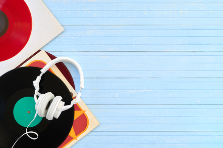 Festive postcard frame. Background of vinyl records DJs for a music player white headphones on a blue wooden background close-up. Red, black vinyl recordの写真素材