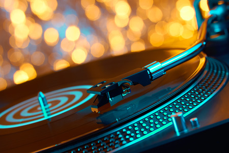 Turntable vinyl record player. Sound technology for DJ to mix & play music. Vintage vinyl record player on a background decorations for a party, bright disco bokeh lights. Needle on a vinyl recordの写真素材