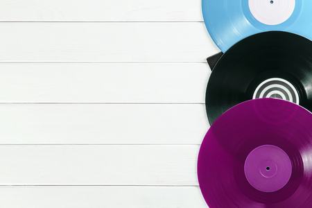 Holiday postcard frame. Background of vinyl records DJs for a music player on a white wooden background close-up. Red, black, violet  vinyl records. Turntable audio equipment for disc jockeyの写真素材