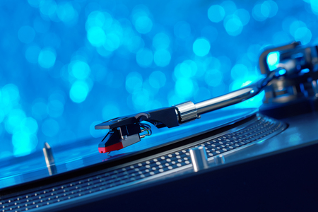 Turntable vinyl record player. Sound technology for DJ to mix & play music. Vintage vinyl record player on a background decorations for a party, bright disco lights. Needle on a vinyl recordの写真素材
