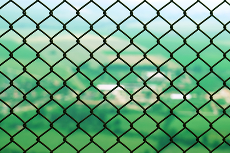 Protective restrictive metal mesh on top of the mountain. Beautiful view of the green summer valley from the top of the mountainの写真素材