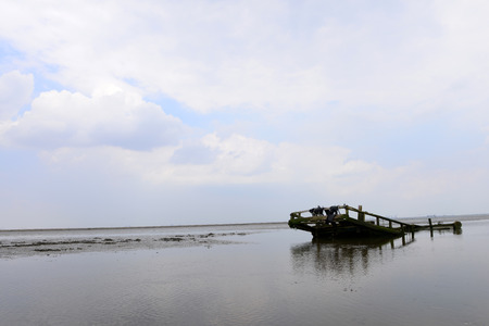 An old fishing boat by the sea under the blue sky white clouds